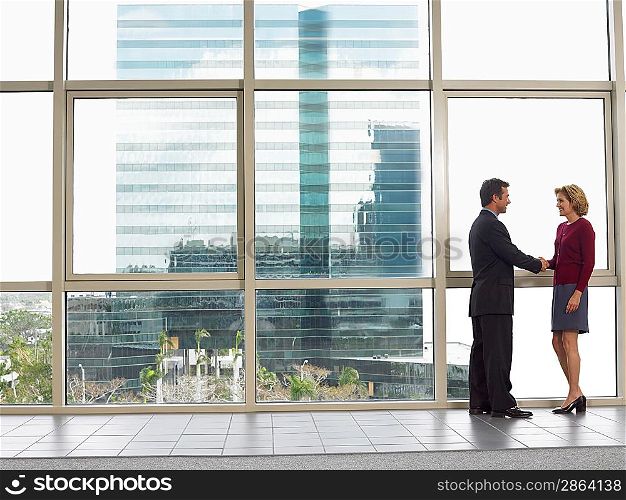 Businessman and woman shaking hands in office building