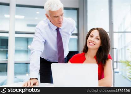 Businessman and young female employee in office. happy to assist with your task