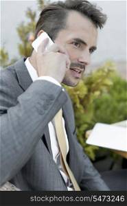 Businessman answering cell phone outdoors