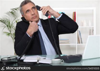 Businessman answering ringing telephones