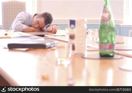 businessman asleep at boardroom table