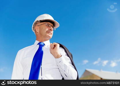 Businessman at construction site. Businesman wearing safety helmet at construction site