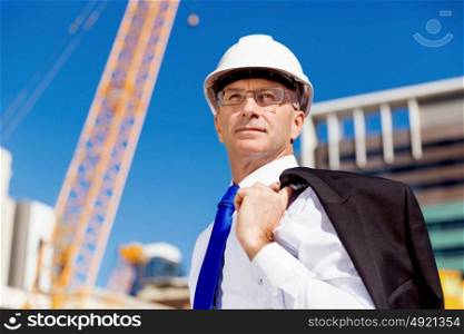 Businessman at construction site. Businesman wearing safety helmet at construction site