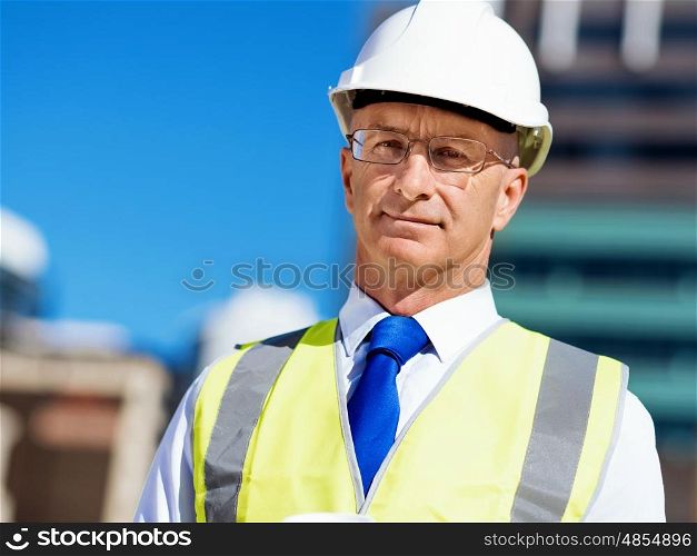 Businessman at construction site. Businesman wearing safety helmetand vest phone at construction site