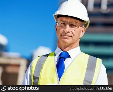 Businessman at construction site. Businesman wearing safety helmetand vest phone at construction site