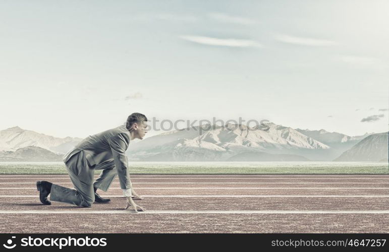 Businessman at start. Young businessman standing in start pose ready to run