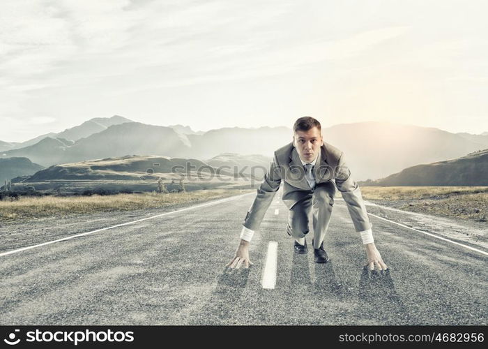 Businessman at start. Young businessman standing in start pose ready to run