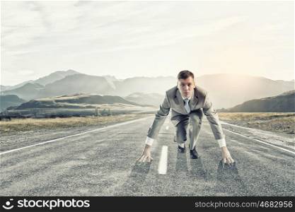 Businessman at start. Young businessman standing in start pose ready to run