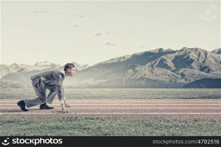 Businessman at start. Young businessman standing in start pose ready to run