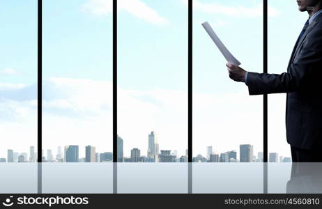 Businessman at work. Businessman standing against office window reading documents