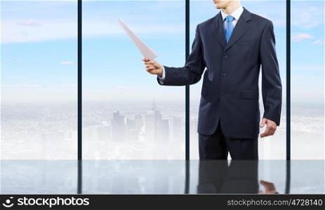 Businessman at work. Businessman standing against office window reading documents