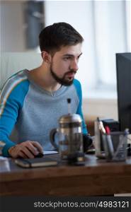 Businessman at work. Handsome young bearded man working on computer while sitting at his office