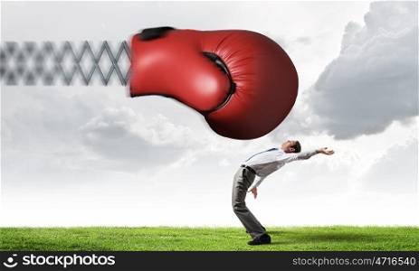 Businessman attacked by glove. Young determined businessman fighting boxing glove on spring