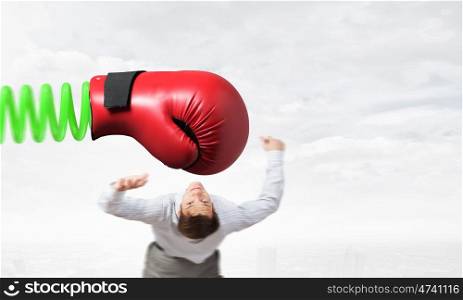 Businessman attacked by glove. Young determined businessman fighting boxing glove on spring