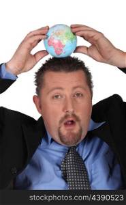Businessman balancing a globe on his head