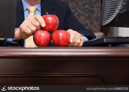 Businessman balancing apples on desk