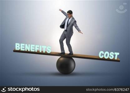 Businessman balancing between cost and benefit in business conce. Businessman balancing between cost and benefit in business concept
