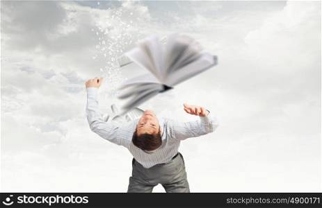 Businessman bent over and evading from book. Man evading flying book