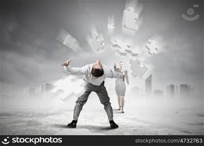 Businessman bent over and evading from flying puzzle element. Man evading flying puzzle