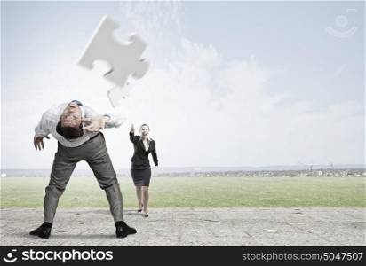 Businessman bent over and evading from flying puzzle element. Man evading flying puzzle