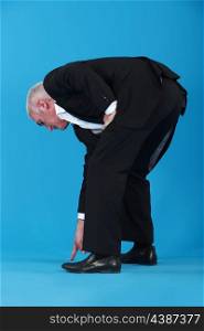 Businessman bent over pointing at shoes