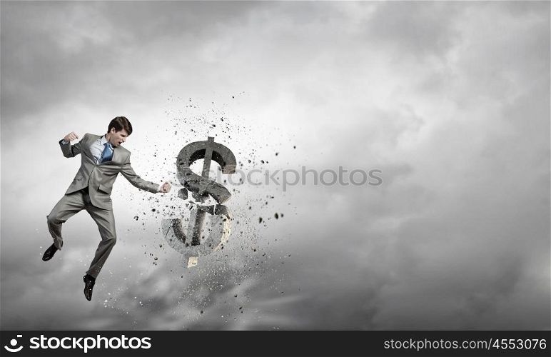 Businessman breaking stone dollar symbol with karate punch. Financial crisis