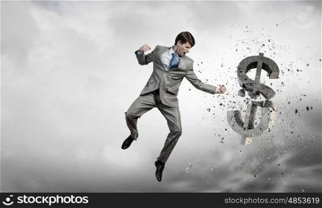 Businessman breaking stone dollar symbol with karate punch. Financial crisis
