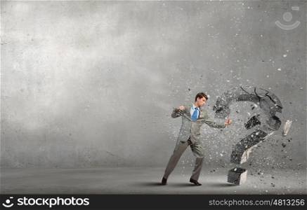 Businessman breaking stone question mark with karate kick. No more questions