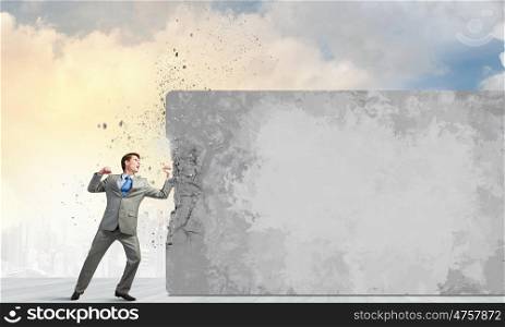 Businessman breaking stone wall with karate punch. No barriers on my way