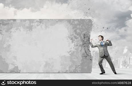 Businessman breaking stone wall with karate punch. No barriers on my way