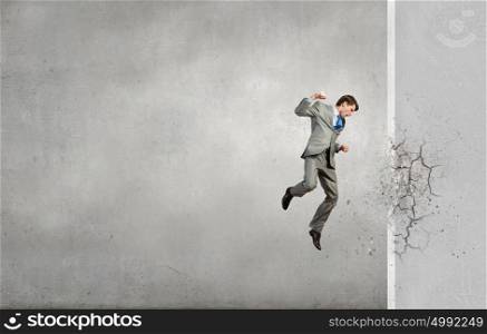 Businessman breaking stone wall with karate punch. No barriers on my way