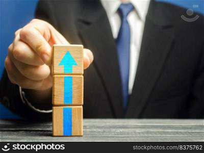 Businessman builds a tower of blocks with an up arrow. Career promotion , growth of professional skills. Business development, expansion improvement. Profit growth. Marketing. Improving efficiency