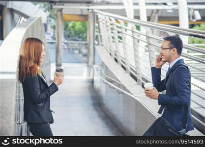 Businessman Businesswoman drinking coffee in town using smartphone outside office modern city. Hands holding take away coffee cup and smart phone talking together Business partner with cup of coffee