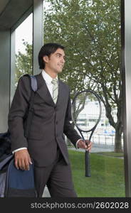Businessman carrying a bag with a tennis racket
