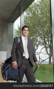 Businessman carrying a bag with a tennis racket