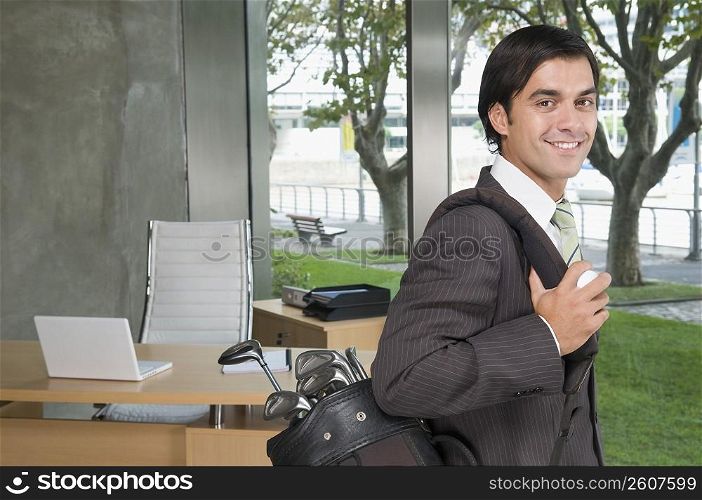 Businessman carrying a golf bag in an office