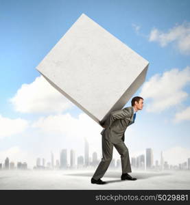 Businessman carrying cube. Image of businessman carrying big white cube on his back