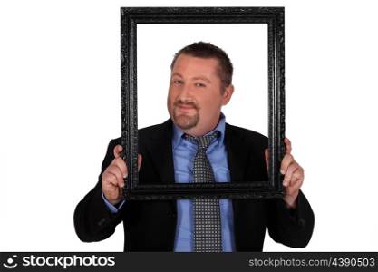 Businessman carrying frame in front of his face