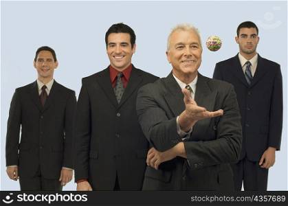 Businessman catching a rubber band ball with three businessmen standing behind him