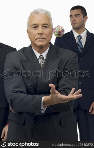 Businessman catching a rubber band ball with two businessmen standing behind him