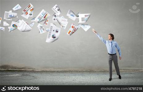 Businessman catching flying papers. Businessman controlling paper documents flying in air