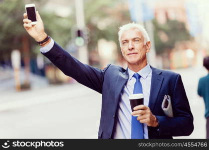 Businessman catching taxi in city. Businessman in suit catching taxi in city with cup of coffee in his hands