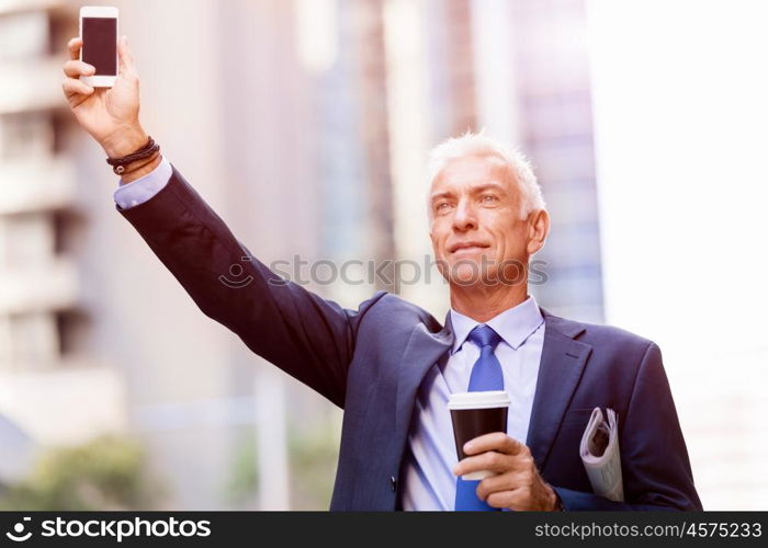 Businessman catching taxi in city. Businessman in suit catching taxi in city with cup of coffee in his hands