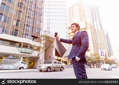 Businessman catching taxi in city. Businessman in suit catching taxi in city with mobile phone in his hands