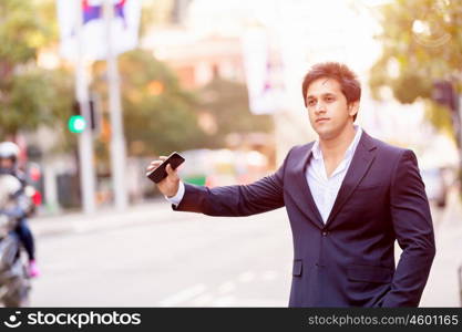 Businessman catching taxi in city. Businessman in suit catching taxi in city with mobile phone in his hands