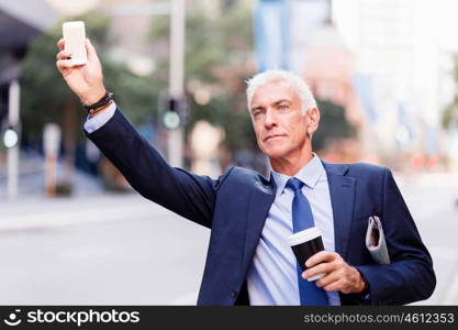 Businessman catching taxi in city. Businessman in suit catching taxi in city with cup of coffee in his hands