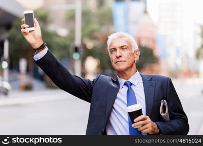 Businessman catching taxi in city. Businessman in suit catching taxi in city with cup of coffee in his hands