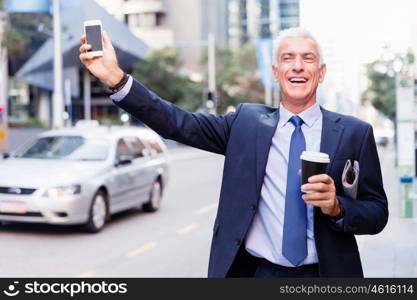 Businessman catching taxi in city. Businessman in suit catching taxi in city with cup of coffee in his hands