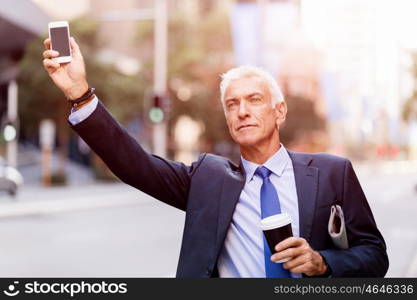 Businessman catching taxi in city. Businessman in suit catching taxi in city with cup of coffee in his hands