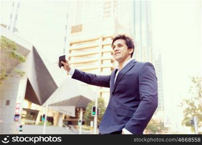 Businessman catching taxi in city. Businessman in suit catching taxi in city with mobile phone in his hands